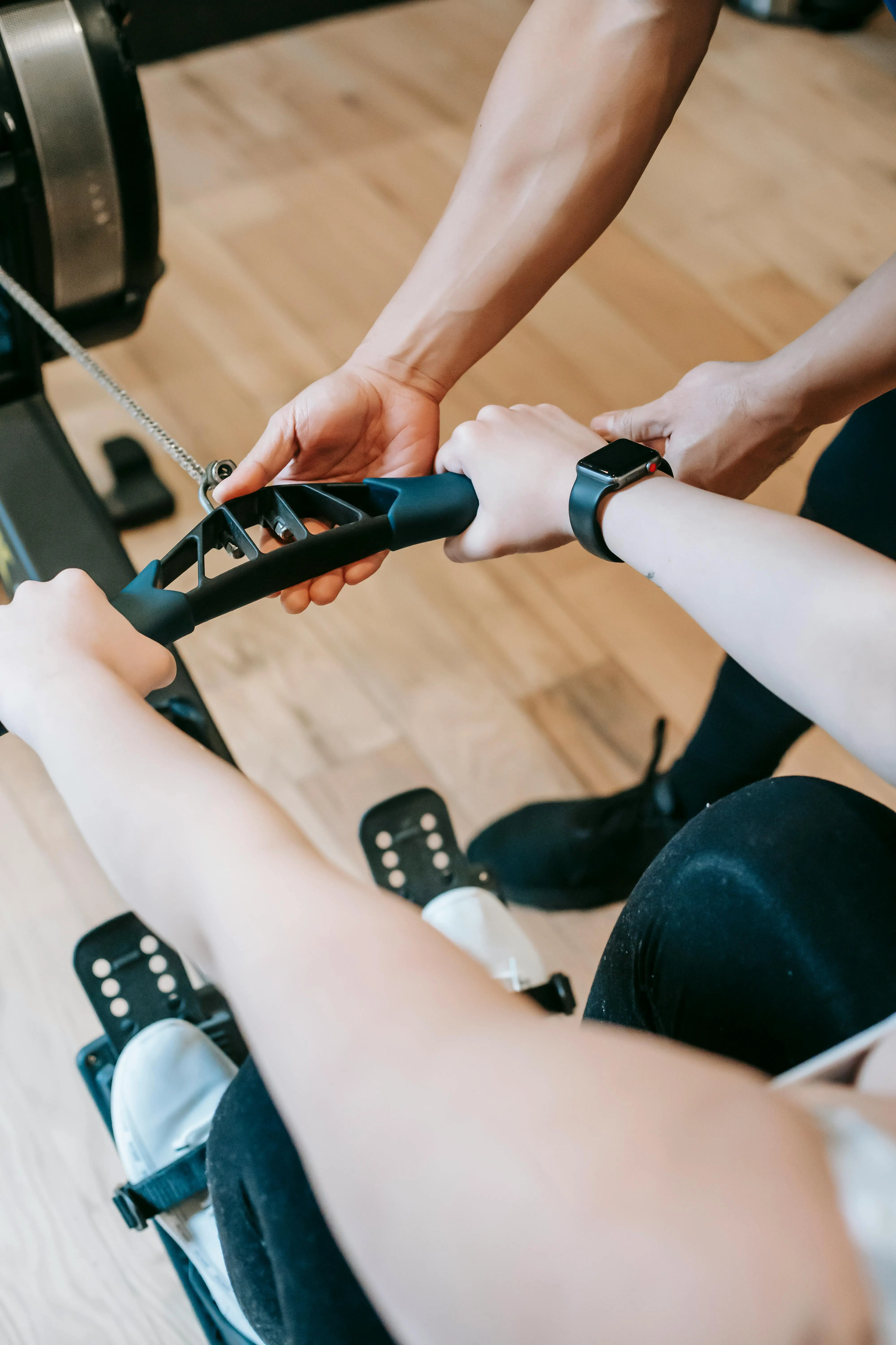 Hands holding a rowing machine handle