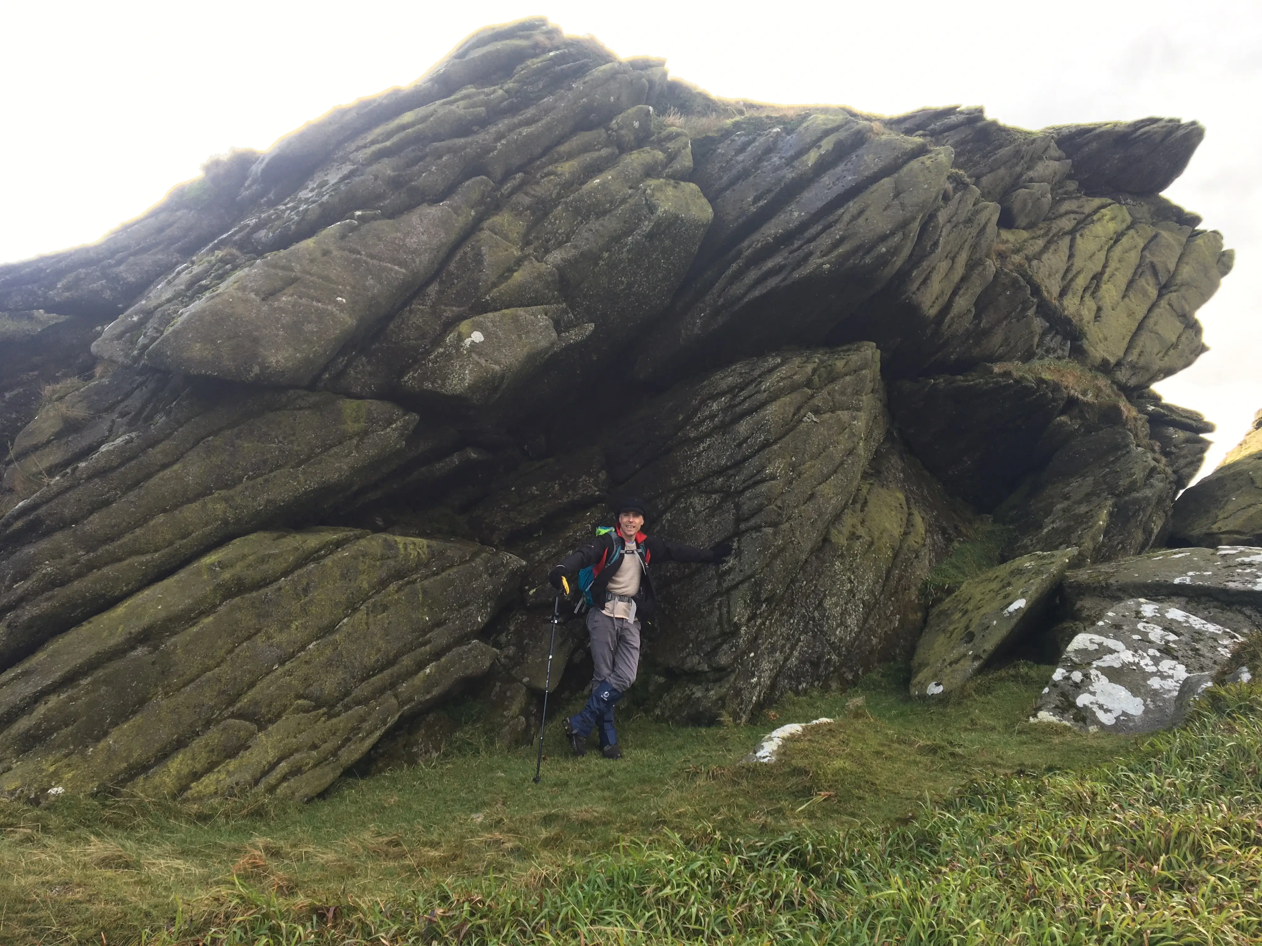 A hiker posing in front of a large rock